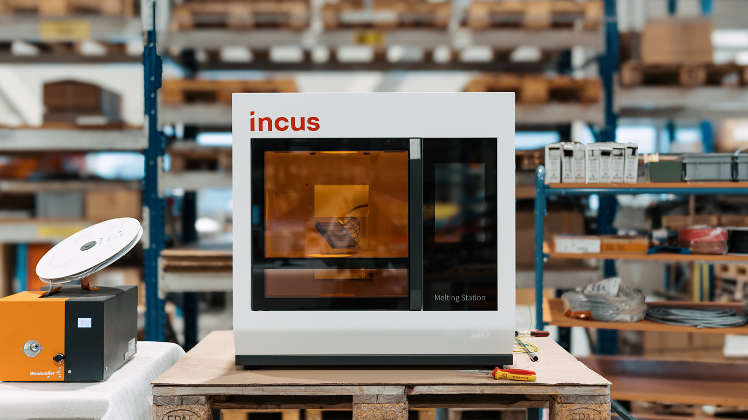 Incus Melting Station in a manufacturing workshop, placed on a wooden pallet.