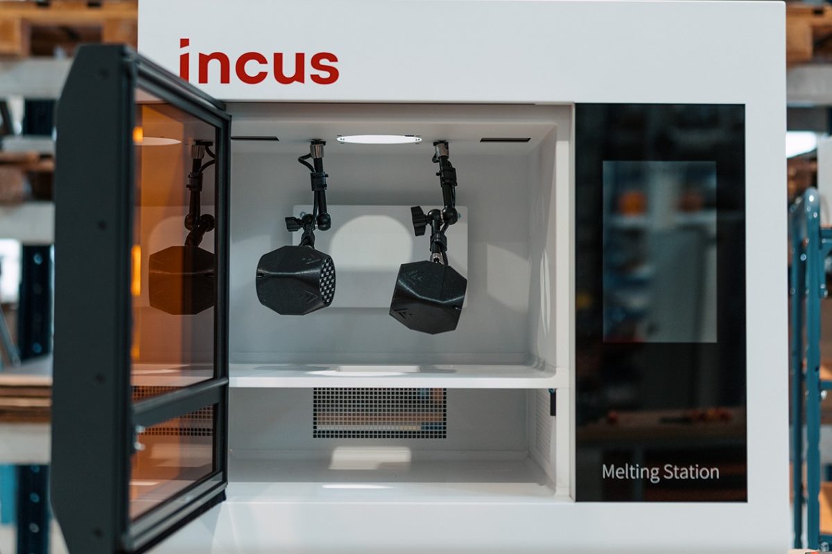 Incus Melting Station with open chamber showing two robotic arms inside for material processing (brand name visible).